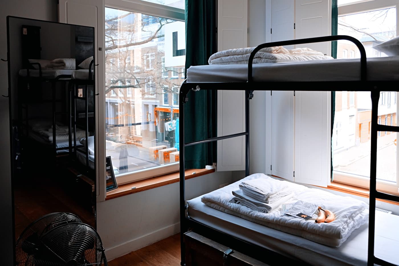 Bright hostel dorm with bunk beds and a window view over a European city street